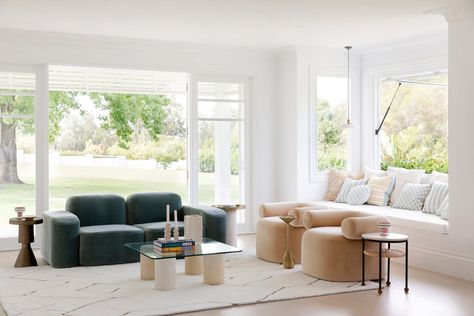 emerald green sofa in white modern living room with glass coffee table and miss amara diamond rug