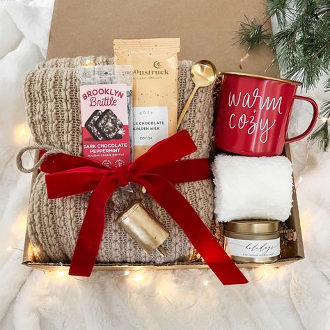 Christmas hygge gift box with cozy throw blanket, red warm and cozy campfire mug, hot cocoa, peppermint brittle, gold spoon, fuzzy socks, holiday scented candle and gold bell ornament perfectly ready to be gifted to anyone on your list. Christmas Self Care Basket, Christmas Basket For Mom, Coffee Cup Gift Ideas Filled, Christmas Gifts For Ladies, Christmas Gifts For Boss, Chocolate Brittle, Coworker Christmas Gifts, Teacher Gifts Christmas, Work Christmas Gifts