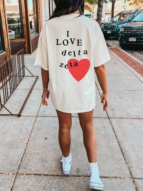 Soft, cute, and trendy, this Delta Zeta sorority t-shirt will quickly become your go-to cozy shirt! Use the drop down to specify preference between white, ivory, island reef, chambray, orchid, or blossom. Printed with black color letters and red color heart.  LISTING IS FOR DELTA ZETA. Please be sure you are ordering for your correct Sorority. We print on high quality, soft, & heavyweight materials, sustainably made and printed in the US. ♥ SIZING ♥ Unisex Sizing- For a more feminine, fitted look we recommend getting your size. For a more oversized look, we recommend sizing up. ♥ SHIP TIME ♥ Items may take up to 7 business days to process before shipping. Shipping time is (on average) an ADDITIONAL 2-5 business days. Shipping times vary for many reasons, but is largely influenced by your l Alpha Chi Omega Merch, Alpha Delta Pi Sorority, Delta Gamma Sorority, Alpha Phi Sorority, Big Little Sorority, Alpha Epsilon Phi, Theta Phi Alpha, Sorority Shirt, Delta Sorority