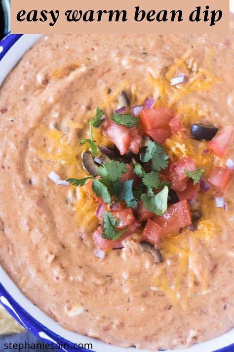 warm bean dip in a white and blue bowl topped with cheese, chopped tomato, chopped black olives, chopped red onion and cilantro Homemade Bean Dip, Cream Cheese Bean Dip, Hot Bean Dip, Mexican Bean Dip, Warm Bean Dip, Easy Bean Dip, Salsa Chili, Refried Bean Dip, Bean Dip Recipe