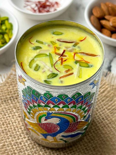 badam milk served in a steel glass garnished with nuts and saffron with nits on the side Badam Milk Recipe, Thandai Recipes, Badam Milk, Saffron Milk, Soaked Almonds, Potato Patties, Dried Fruit Mix, Dry Fruit, Pineapple Smoothie