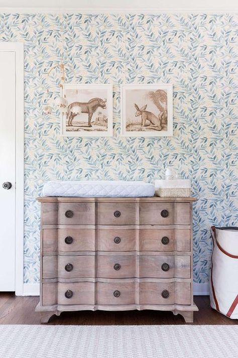 Lulu & Georgia Whispering Leaves wallpaper covers the wall of this welcoming nursery featuring animal print art hung over a French dresser changing table. Nursery Wallpaper Ideas, Vintage Animal Prints, Gender Neutral Nursery Design, Nursery Design Neutral, Lulu Georgia, Bohemian Nursery, Changing Table Dresser, Fun Nursery, Big Kids Room