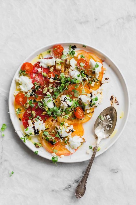 A raw Heirloom Tomato Carpaccio made with thinly sliced heirloom tomatoes, fresh burrata cheese, pistachios, corn, and microgreens. Tomato Carpaccio, Summer Tomato Recipe, Heirloom Tomato Recipes, Italian Side Dishes, Broma Bakery, Italian Side, Lots Of Food, Summer Tomato, Heirloom Tomato