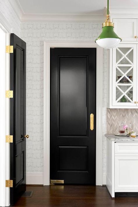 A French-style black pantry door is complemented with brass hardware and lit by an emerald green lantern. Collins Interiors, White Kitchen Pantry, Antique White Cabinets, Kitchen Pantry Doors, Warm Wood Flooring, Black Interior Doors, White Tile Backsplash, White Shaker Cabinets, White Backsplash