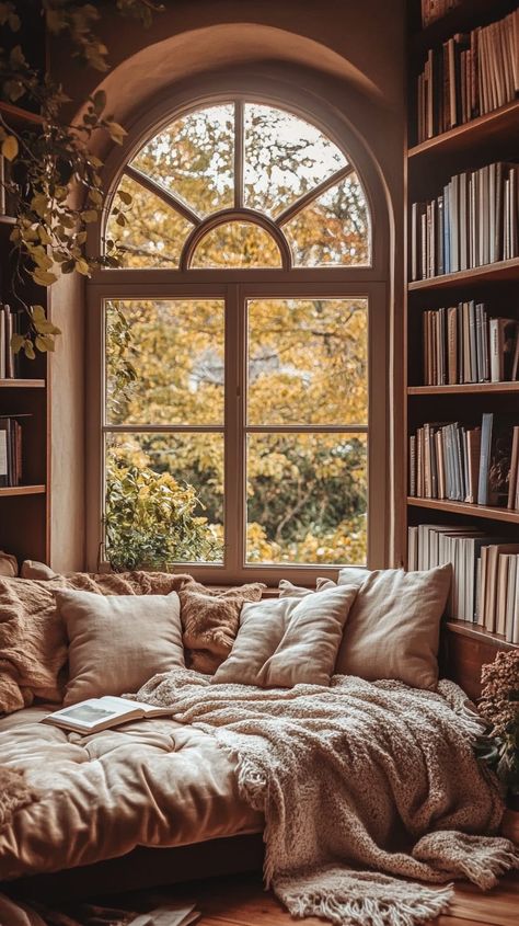 Cozy reading nook with plush cushions, blankets, arched window, and bookshelves in warm tones for serene contemplation. Book Girl Room, Books Aesthetic Bedroom, Bookish Bedroom Aesthetic, Bedroom With Library, Closet Turned Into Reading Nook, Book Bedroom Ideas, Bedroom With Books, Bookish Bedroom, Home Library Aesthetic