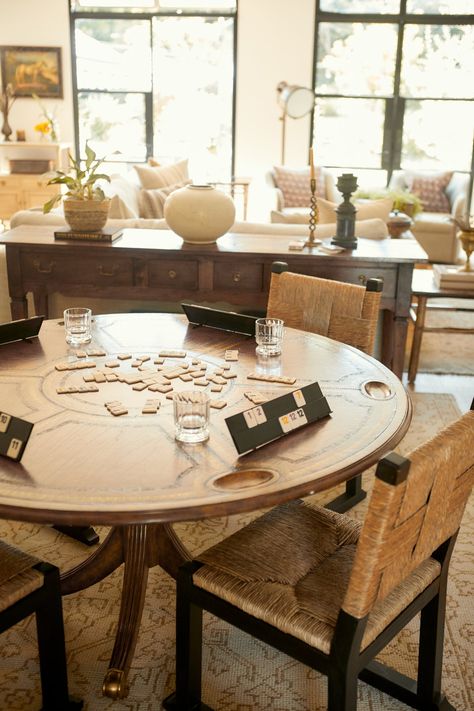 A leather-topped game table, which was a popular piece of furniture in homes where social games were a common pastime. The circular shape of the table provides an intimate setting for card games or board games, accommodating multiple players comfortably. The tabletop is inlaid with a tooled leather surface, which provides a soft, tactile, and durable area for placing cards and game pieces. The leather is embossed with gold tooling to delineate playing areas and to add an element of luxury and de Game Table In Front Of Fireplace, Round Table Game Room, Table Top Game Room Ideas, Game Table Room, Basement Game Table Ideas, Basement Card Table Ideas, Classic Game Room, Round Game Table In Family Room, Elegant Game Room