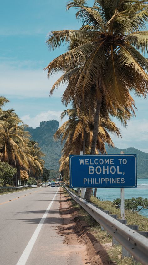 Welcome to Bohol, Philippines" sign by a palm-lined road, with mountains, the sea, and a clear sky in the background. Bohol Chocolate Hills Philippines, Philippines Vision Board, Bohol Philippines Aesthetic, Philippines Province Aesthetic, Philippines Holiday, Philippines Nature, Philippines Bohol, Philippines Aesthetic, Panglao Bohol