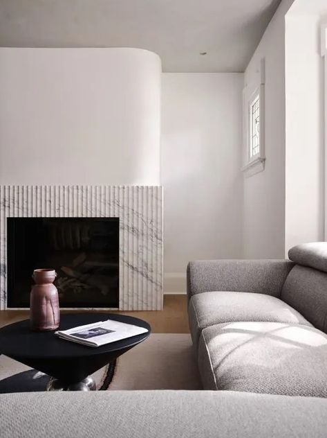 a minimalist space with a fireplace with a fluted surround, a large grey sectional and a black coffee table with decor Fluted Fireplace, Shared Home Office, Minimalist Fireplace, White Staircase, Minimalist Space, Black Fireplace, Double Sided Fireplace, Neutral Furniture, Park House