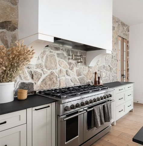 Black Countertop Stone Backsplash, White Kitchen Cabinets Black Countertops Stone Backsplash, Black Countertops Stone Backsplash, Stone Behind Range, Gorgeous Backsplash Kitchen, Stone Range Hood Kitchen, Stone Accent Walls Kitchen, Stove Alcove Kitchen Stone, Stone Backsplash Black Countertop