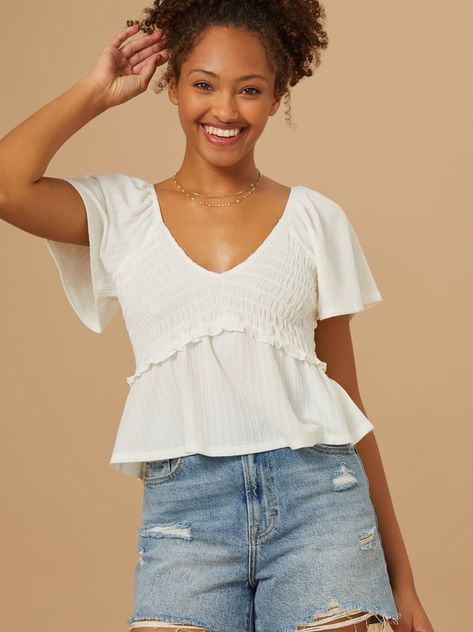 This top is so versatile, and can be dressed up or down depending on your plans. We love the v-neck cut of this top for a feminine vibe, and the smocked detailing makes this sure oh-so-comfortable. Cute Tops Modest, Cute Flowy Tops, Modest Fits Aesthetic, Cute Tops For School, Nice Shirts For Women, Cute School Outfits For Middle School, College Tops, Ruffle Shirts, White Babydoll Top