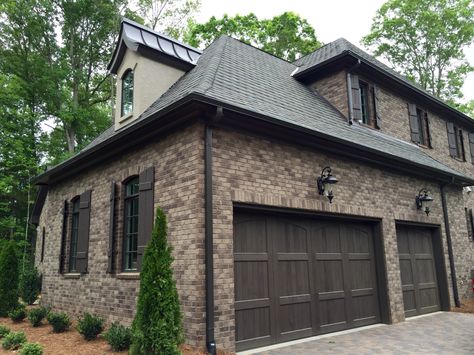 ARH Asheville 1131F Plan (Exterior 40) Stone: Oakridge (gray mortar), Brick: Boral Bastille, Room: Grand Manor Tudor Brown, Metal Roof: Dark Bronze, Soffits/Fascia/Trim: SW7020 Black Fox, Stucco: #210 London White, Window Frames: SW7038 Tony Taupe, Shutters/Columns/Cedar Brackets: SW3001 Shagbark, Entry Porch: Crab Orchard Brown, Front Door/Garage Door Stain: SW3518 Hawthorne, Rear Porch Flooring: Daltile Ayers Rock Majestic Mound (Grout #165 Delorean Gray) Brown Brick Exterior, Brown Garage Door, Brown Brick Houses, Grey Exterior House Colors, Gray House Exterior, Brown Brick, House Exterior Colors Schemes, Garage Door Design, Brick Exterior House