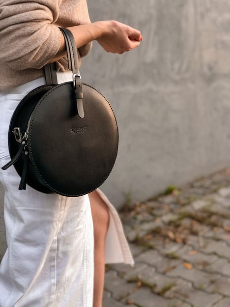 "Leather circle crossbody bag with a convenient harness for carrying on the shoulder and a handle for carrying the bag in hand.  There is a pocket on the outer back of the bag.  Material: Italy Leather  Color of the leather: black Hardware: Italian fittings of high quality Hardware color: nickel  Overall size: diameter  9.44 \" in / 24 cm  thickness  3.14\"  in /  8 cm  Strap size: width 0,59\" in /  1,5 см length   51,18\"in / 130см     Handle size: width   0,98\"in / 2,5 см ------------------- Bag Leather Handmade, Round Crossbody Bag, Crossbody Saddle Bag, Round Purse, Circle Bag, Luxury Crossbody, Round Bag, Round Leather, Leather Bag Women