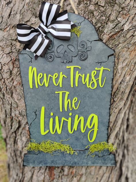 This Never trust the living tombstone adds the perfect  touch to your door for Halloween. It measures around 23 inches tall and 15 inches wide, its hand painted, layered, then topped with green moss and a bow! You can choose to purchase this with a hanger on the back for a doorhanger or without a hanger as a porch leaner! Each one is lasered out of 1/4inch wood, hand painted, personalized, and sealed. We pride ourselves in excellent turn around time. Each sign is made in the order it is received. Please allow 1- 2 weeks for us to complete your order. In some cases, you may get it sooner! If there is ever a reason that your sign will be delayed, I promise to communicate an expected shipment date. *All signs are sealed to protect the finish, if you are displaying outside in an uncovered area Beetlejuice Porch Sign, Beetlejuice Sign Diy, Beetlejuice Diy Decorations, Beetlejuice Outdoor Decorations, Beetlejuice Halloween Decorations Diy, Halloween Sign Ideas, Beetlejuice Decorations Diy, Halloween Signs And Sayings, Here Lies Beetlejuice