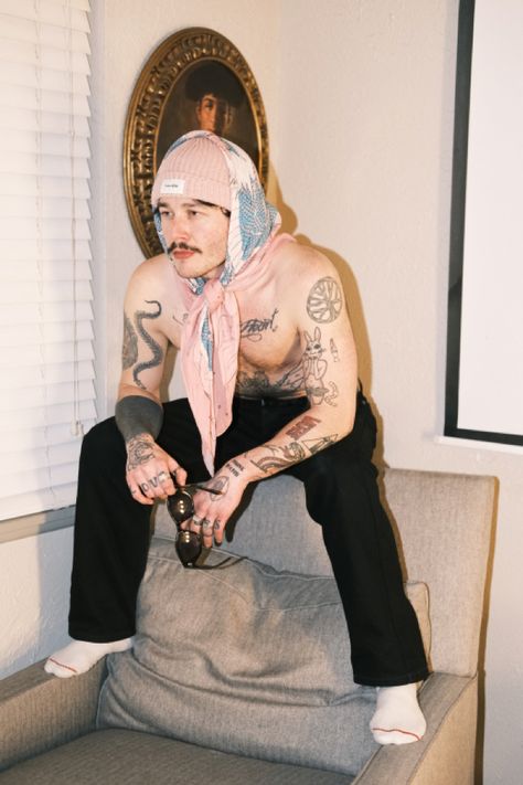 Man wearing dragon print scarf over beanie sitting on top of chair. Men In Head Scarfs, Silk Scarf Outfit Men, Bandana Outfit Men, White Sunglasses Outfit, Outfits With Scarf, Scarf Outfit Men, Summer Fits Men, Mens Scarf Fashion, Silk Scarf Outfit