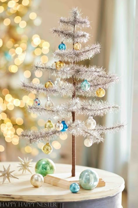 If you're into a bit of nostalgia, check out this Vintage Tinsel Christmas Tree DIY. They're a shimmering, glitzy throwback, perfect for adding old-school sparkle and charm to your holiday decor. Silver Tinsel Christmas Tree Vintage Ornaments, Mini Tinsel Christmas Tree, Vintage White Christmas Tree, Vintage Tinsel Christmas Trees, Tinsel Earrings, Kitchen Christmas Tree, Silver Tinsel Tree, Paper Wreath Diy, Merry Creepmas