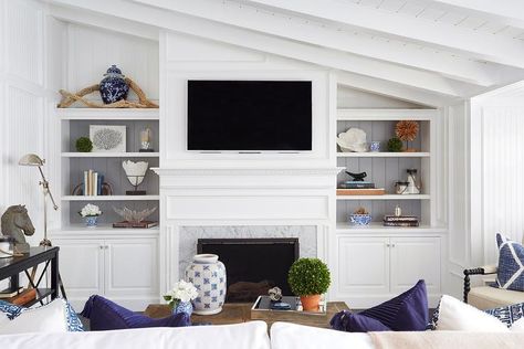 Chic living room features a sloped ceiling over a flat screen tv and white dentil fireplace mantle accented with carrera marble flanked by built-in bookshelves with backs of shelves lined with gray shiplap trim. Built In Around Fireplace, Marble Room, Fireplace Bookshelves, Shiplap Ceiling, Built In Shelves Living Room, Living Room Built Ins, White Shiplap Wall, Shiplap Fireplace, Slanted Ceiling