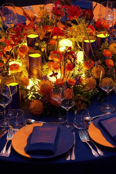 The table setting and scenography for the Guggenheim International Gala's dinner transformed the museum into a fantastical garden. Projections of flowers in an electric blue hue contrasted with the warmly lit tables for a colorful display of lights. From an aerial view, the Dior Maison table settings give the illusion that they are flowers themselves with illuminated centerpieces. © Reed Young Skirt Shapes, Saddle Club, 70th Birthday Decorations, Gala Party, Gala Ideas, Orange Table, Hand Painted Glasses, Gala Events, Dinner Decoration