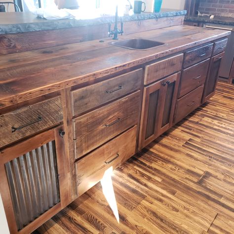 Kitchen of your dreams? Ours too! Check out the live edge concrete, corrugated tin in the doors, and open shelving under the cabinets. This is a show stopper. Custom build just for this space. Come design your dream kitchen with us! 
#Reclaim Renew #customkitchen #kitchen #eat #custom #custombuild #corrugatedtin #barnwood #rustic #farmhouse #style Rustic Cabin Kitchens Open Shelves, Farmhouse Kitchen Open Cabinets, Kitchen Cabinet Rustic Farmhouse Style, Under Counter Cabinet Ideas, Rustic Tin Cabinets, Corrugated Tin Cabinets, Rustic Cabinets Farmhouse Style, Glazed Kitchen Cabinets Farmhouse, Barnwood Cabinets Kitchens