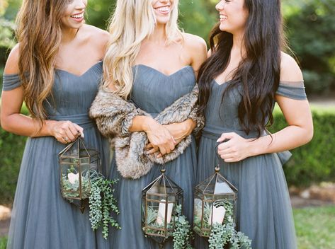 three bridesmaids pose together in eucalyptus tulle convertible dresses. Bridesmaids hold candle filled lanterns instead of bouquets. Center bridesmaid with fur for winter wedding vibes. Spring Bridesmaids, Bouquet Alternatives, Mixed Bridesmaid Dresses, Oct Wedding, Bridesmaid Bouquet Alternatives, Alternative Bridesmaid, Wedding Bridesmaid Bouquets, Bridesmaid Poses, Winter Bridesmaids