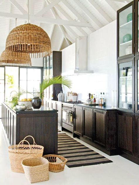 a bold tropical kitchen with white walls, dark stained cabinets, woven pendant lamps and baskets plus tropical leaves Minimalist White Kitchen, Tropical Kitchen Design, Tropical Kitchen Decor, Dark Stained Cabinets, Neutral Kitchen Designs, Stained Cabinets, Decor Kitchen Ideas, Tropical Kitchen, Coastal Kitchen Design