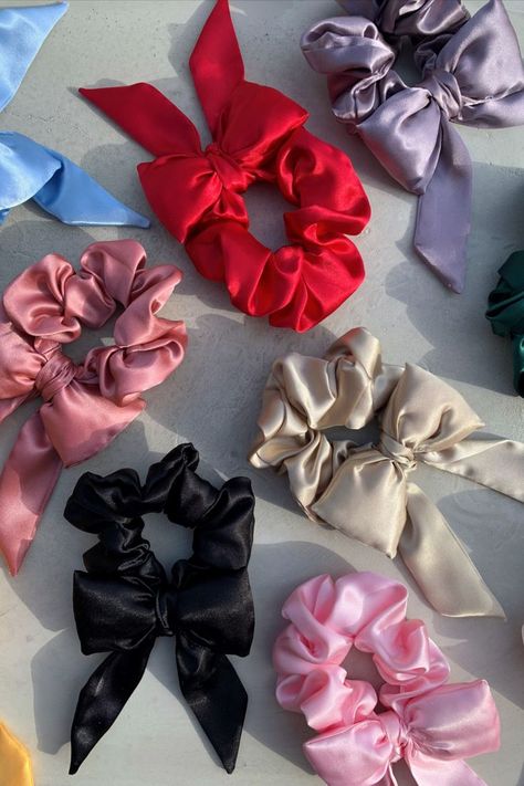 Colored satin, short tail, hair bow scrunchies lying about on a cement background. The colors that can be seen are lavender, forest green, red, ice blue. rose, marigold, black, pink, and champagne.. Everyday Ponytail, Fragrance Quote, Scrunchies Diy, Tail Hair, Bow Hairstyle, Hair Elastics, Head Accessories, Indian Hairstyles, Scrunchie Hairstyles