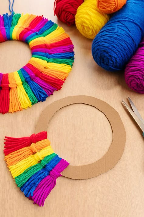 Make a rainbow tassel wreath using colourful yarn and a piece of cardboard! This rainbow craft is SO EASY to make, perfect for kids of all ages and adults. This homemade decor looks so beautiful on display, and you can make it using simple craft supplies. Holiday Yarn Crafts, Cardboard Wreath Form, Tassel Wreath, Diy Yarn Decor, Craft For All Ages, Door Toran, Easy Yarn Crafts, Rainbow Craft, Make A Rainbow