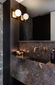 In this modern powder room, metallic accents have been paired with dark stone and black walls for a bold and dramatic appearance. #ModernPowderRoom #BathroomDesign Bathroom Without Windows, Modern Powder Rooms, Modern Powder Room, Glamorous Interiors, Dark Bathrooms, Powder Room Design, Modern Toilet, Bad Inspiration, Black Bathroom