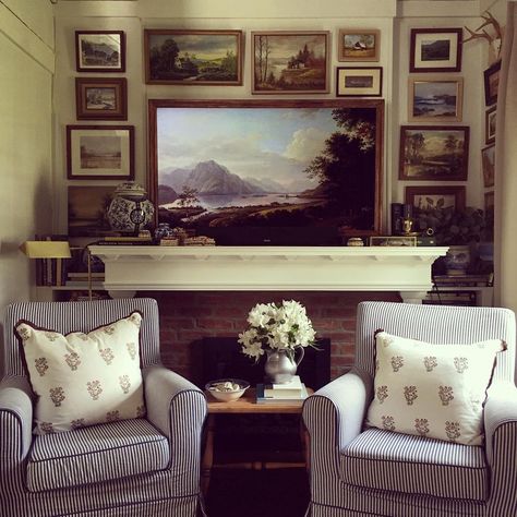 Relax in this vintage living room with a gallery of framed art above the fireplace. The fireplace is decorated with antique collectibles on a white mantel. Comfortable furniture, such as armchairs paired with soft cushions, enhance the cozy ambiance. Modern Vintage Living Room, White French Doors, Modern Farmhouse Entryway, White Homes, Picture Wall Ideas, White Mantel, Above Fireplace, Above The Fireplace, Photograph Display