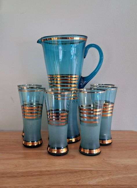 Mid-Century Modern Blue and Gold Pitcher Set - Vintage Glassware with 6 Glasses | Collectible Drinkware | Retro Barware **Description Elevate your entertaining with this stunning Mid-Century Modern Blue and Gold Pitcher Set. This exquisite set includes a large pitcher and six matching glasses, all featuring a beautiful blue hue with elegant gold bands. Perfect for serving your favorite beverages in style, this vintage glassware set brings a touch of retro sophistication to any occasion. Crafted Mid Century Glassware, Cocktail Glassware, Pitcher Set, Lake House Plans, Glassware Set, Drinking Set, Vintage Dishes, Classic Cocktails, Mid Century Modern Style