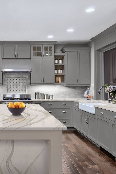 Amazing kitchen designed shaker gray cabinets with Cambria Brittanicca Gold quartz countertop and dark hardwood floor. #cambriabrittaniccagoldquartzcountertop #cambriabrittaniccagoldquartzkitchencounter #cambriabrittaniccagoldquartzkitchentop #cambriacolors #cambriacountertop #graykitchencabinet #graycabinetry #graycupboard #greycabinet #darkplankfloor #darkporcelainfloor #darkceramicflooring #whitesubwaytile #whitemarblesubway #whitemarblebacksplashtile #whitefarmhousesink #whiteapronsink Cambria Quartz Kitchen Countertops, Kitchen Countertops Ideas, Countertops Ideas, Kitchen Cabinet Color Ideas, Light Grey Kitchens, Kitchen Design Gallery, Bloxburg Kitchen, Grey Kitchen Designs, Cambria Quartz