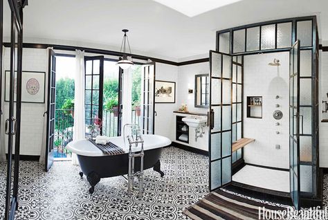 Skylight over steel and frosted glass glass shower with double doors adorned with subway tiled surround, teak shower bench, tiled shower niche and diamond pattern shower floor. Floor to ceiling subway tiled walls are accented with black crown moldings and black base boards frame mirror over wall-mounted sink flanked by built-in cubbies across from black clawfoot bathtub atop black and white quatrefoil tiled floor placed in front of black French doors covered in white curtains. Spanish Bathrooms, Bathroom Industrial Chic, Casita Ideas, Bold Tile, White Bathroom Designs, Victorian Bathroom, Industrial Bathroom, Bad Inspiration, Architectural Styles