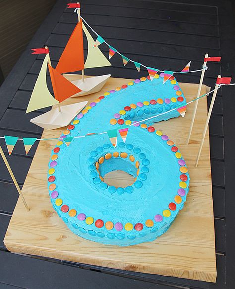 number cake with sailboats + bunting {tip: the serving tray is not wood...it's a sheet of styrofoam covered in woodgrain Contact paper! Cheap, easy to clean, and you can secure items to it!} Sixth Birthday Cake, Sailboat Cake, Boat Cake, Number Birthday Cakes, 6th Birthday Cakes, Messy Kids, Cupcake Birthday Cake, Nautical Birthday, Gateaux Cake