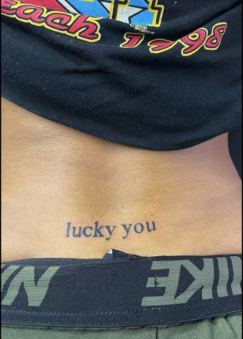 Lucky U Tattoo, Tramp Tattoos For Women, Stamp Tramp Tattoo Lower Backs, Tramp Stamp Words Tattoos, Trap Stamp Tattoos Black Women, Lower Back Tattoos For Women Words, Lucky You Tattoo Tramp Stamp, Lower Back Tattoo Black Women, Baddie Tramp Stamp Tattoos