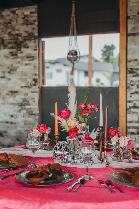 It was so fun to style this disco ball themed table! We used bright pink linens, pink flowers in assorted bud vases, vintage style candlestick holders, and of course disco balls! Gold chargers and clear plates completed the place settings along with brown napkins and antique silverware. Pink And Orange Disco Ball Wedding, Disco Wedding Centerpieces, Bridal Shower Pink Theme, Disco Reception, Brown Napkins, Themed Bridal Shower Ideas, Community Heroes, Cheesecloth Runner, Round Table Settings