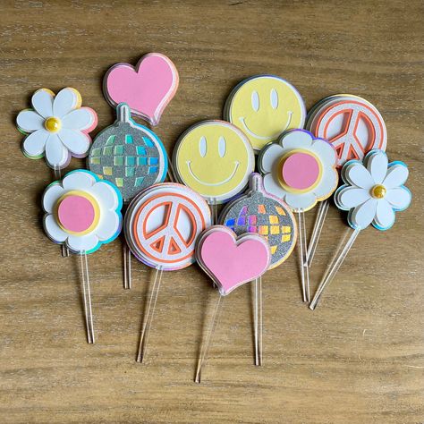 These handmade beach themed cupcake toppers feature groovy elements: happy face, heart, peace sign, 2 flowers, and a disco ball with a pastel and holographic color scheme  Size: 2 inches wide Matching Banners:  Matching Cake Topper:  DISCLAIMERS: Please note that I take all photographs to best represent accurate colors, however, colors may differ slightly from the color presented on the screen.  Paper products should be handled with care. Banners Matching, Groovy Elements, Beach Theme Cupcakes, 12th Birthday Party Ideas, Matching Banners, Peach Lavender, Peace Heart, Holographic Color, Disco Theme