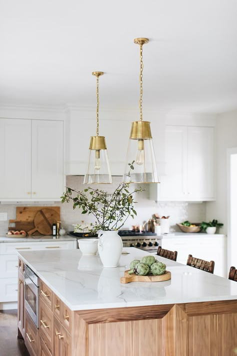 Oak Lake House remodel by Laura Design Company. White cabinets, medium-brown wood floor tones, natural walnut stained island, quartzite counters, and brass hardware accents updated this space. A beaded chandelier hangs over the custom reclaimed turn-legged dining table. Woven chairs, leather counter stools, and a vibrant red vintage rug provide warmth and character. Lighting is by Visual Comfort, faucets by Waterstone. Floor stain is a mix of coffee and neutral. Built-in microwave drawer. Walnut Island, Complete Kitchen Remodel, Renovated Kitchen, Wood Island, New House - Kitchen, White Countertops, Elegant Kitchens, Kitchen Cabinet Colors, Transitional Kitchen