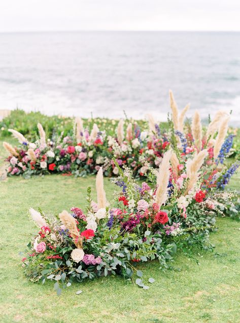 Colorful Organic Ceremony Ground Arch with pampas grass, roses, and eucalyptus. Beach wedding on the grass. Cavin Elizabeth Photography Wedding Ceremony Pampas, Pampas Ground Arch, Floor Flower Arch Wedding, Wedding Ground Arches, Ceremony Ground Arrangements, Grounded Ceremony Arch, Ground Wedding Arch, Ground Arch Wedding Ceremony, Grounded Arch Wedding Ceremony