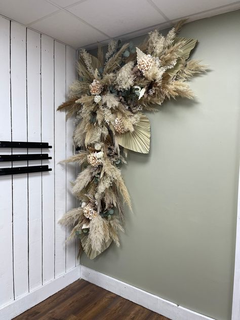 This stunning pampas, dried foliage, palm spear and artificial flower corner swag is perfect to make a statement  This can be brought and posted or we can install locally.  If purchased this will be shipped in sections (depending on size) with instructions how to hang.  Lead time for postage is 10 working days  We also offer installation locally offering to the following areas;  Walsall  Cannock  Wolverhampton  Sandwell And some surrounding areas  If purchasing for installation, please drop us a message as you can pay a deposit to secure your date and the balance of completion Dried Flower Arrangements Above Fireplace, Boho Hanging Flower Wall, Pampas Grass Bedroom Mirror, Dried Palm Frond On Wall, Dried Palm Wall Art, Faux Flower Wall Hanging, Dried Palm Leaves Wall Hanging, Silk Flowers Hanging Display On Wall, Flowers To Hang On Walls