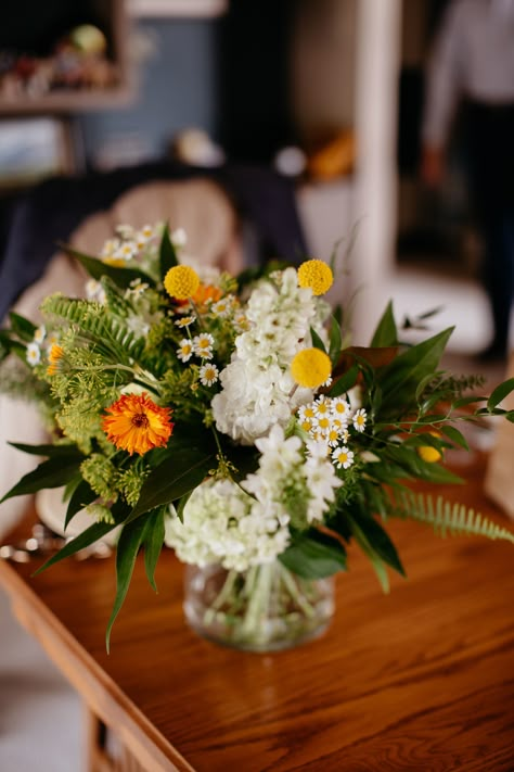 A bridal bouquet in white and green with pops of orange and yellow. This bouquet includes ferns, stock, feverfew, craspedia, calendula, gold grevelia, queen annes lace, phlox. A july wedding in wyoming with flowers by sheridan, WY wedding florist whirly girl flowers. Green Bride Bouquet, Green And White Bridal Bouquet, Fern Centerpiece, Green And White Wedding Flowers, Intimate Family Wedding, Wyoming Elopement, Copper Wedding Arch, White And Green Bouquet, Fern Bouquet