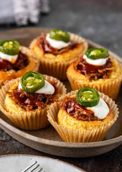 Fluffy stuffed cornbread muffins are packed with saucy pulled pork and topped with spicy candied chiles — a super fun and unique BBQ treat! Pork Hors D'oeuvres, Pulled Pork Fingerfood, Pulled Pork Stuffed Cornbread Muffins, Pot Roast Cornbread Cupcakes, Stuffed Cornbread Muffins, Rodeo Themed Snacks Food Ideas, Wild West Appetizers, Pork Rind Muffins, Mini Cornbread Chili Cups