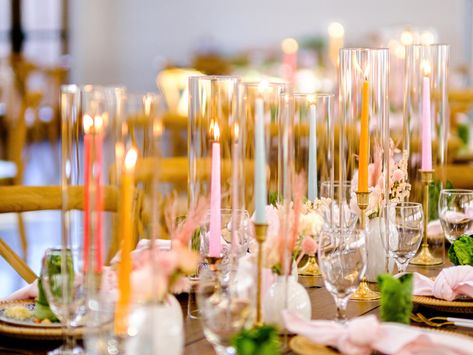 Utilizing colorful pastel taper candles in brass candlesticks and glass hurricanes intermingled with bud vases for long tables as a wedding centerpiece to add color and ambiance to your tablescape. Bud Vases With Taper Candles, Pastel Candles Wedding, Candle Stick Centerpiece, Combermere Abbey, Round Table Centerpieces, Table Scaping, Taper Candles Wedding, Candles For Wedding, Colored Taper Candles