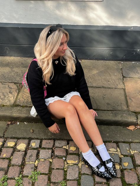 a blonde woman wearing black square prada sunglasses, pink monogram coach soho shoulder bag, silver heart choker necklace, black knitted jumper, white frilly broderie anglaise mini skirt, white socks, black pointy ballet flats with studs and buckles Pointy Ballet Flats Outfit, Pointy Ballet Flats, Pointy Flats Outfit, Pink Ballet Flats Outfit, Pink Flats Outfit, Autumn Outfits 2023, Trans Outfit, Sandals With Socks, Autumn Outfit Inspo