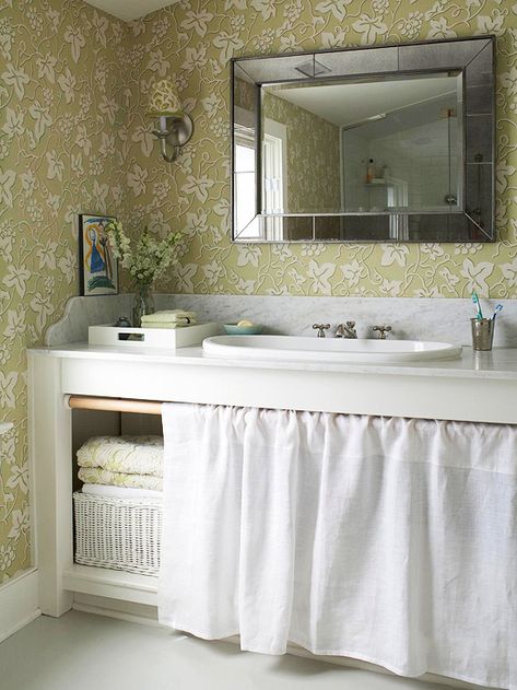 A Classic Approach Give your bath a timeless look by splurging on a marble countertop and save on inexpensive cabinetry. This simple marble-topped workbench-style vanity provides room for towels and toiletries under the sink. Simple cotton skirting, instead of traditional doors, keeps the items under wraps. Flirty green floral wallpaper adds cottage style that's easy to update in the future. Door Curtains Kitchen, Modern Style Decor, Farmhouse Backsplash, Unique Backsplash, Kabinet Dapur, Bad Inspiration, Vanity Design, Small Bath, Bad Design