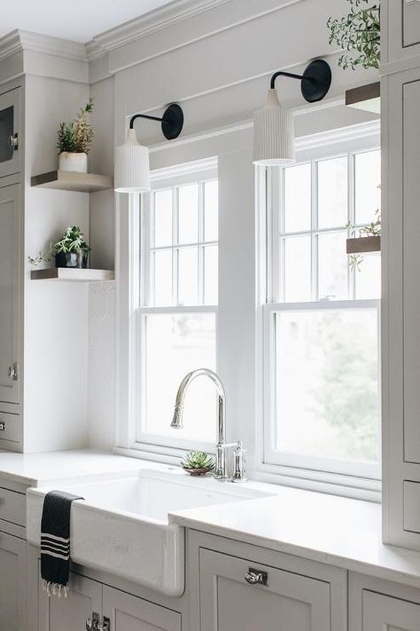 Vintage fluted sconces light a farmhouse sink fitted with a chrome gooseneck faucet mounted to a white quartz countertop over white cabinets. Interior Design Pantry, Kitchen Sconces Over Sink, Lights Over Kitchen Sink, Kitchen Windows Above Sink, Storage Interior Design, Light Above Kitchen Sink, Lighting Above Sink, Over Sink Lighting, Before And After Home Interior