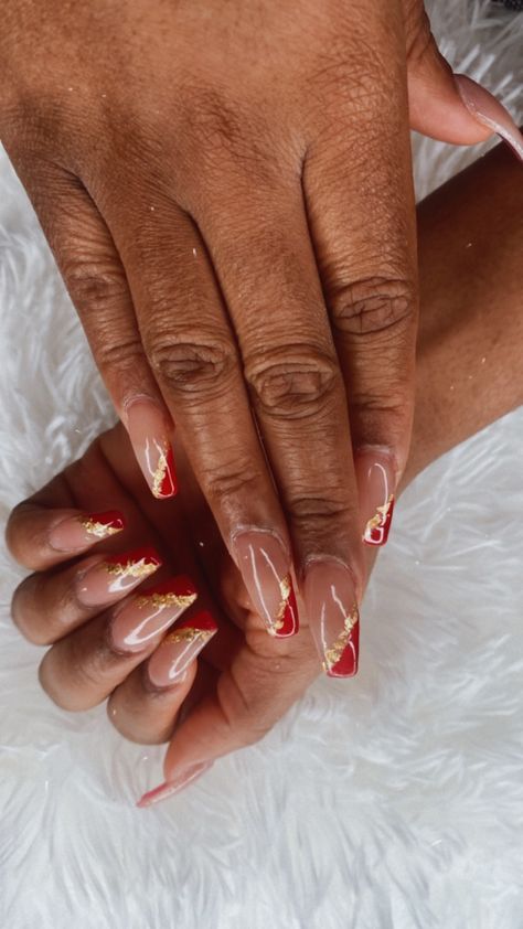 Red coffin nails with a nude base and gold flakes Red And Gold Nails Medium, Elegant Red And Gold Nails, Gold Red And White Nails, Nails That Go With Red Dresses, 49ers Acrylic Nails, Red Ball Nails, Prom Nails That Go With A Red Dress, Gold Red Bottom Nails, Gold With Red Nails