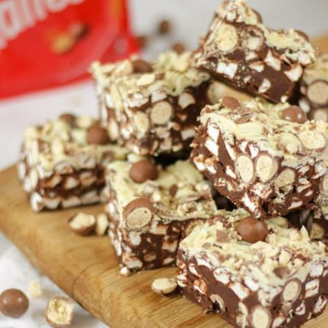 Side angle photo of a pile of Malteser Rocky Road pieces on a wooden board with pack of Maltesers in the background. Malteser Rocky Road, Taming Twins, Malteser Cake, Maltese Recipes, Rocky Road Recipe, Fridge Cake, Tray Bake Recipes, Hazelnut Cake, Sweet Treats Desserts