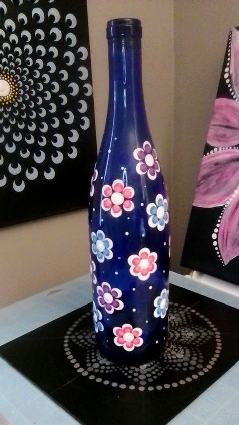 This unique wine bottle has been intricately hand painted with a beautiful dot mandala design. The stunning blue color and delicate flower theme make it a perfect decorative piece for any room in your home. This decorative bottle is a one-of-a-kind piece, perfect for anyone who appreciate art and unique home décor.  The style of this bottle is both modern and classic, making it perfect for any type of home. With hand-painted dot details and decorative features, this bottle is sure to be a conver Glass Bottle Art Diy Craft Projects, Glass Bottles Painting, Glass Bottle Painting, Bottle Art Projects, Unique Wine Bottles, Blue Wine Bottles, Pink Mason Jars, Crafts With Glass Jars, Wine Bottle Wind Chimes