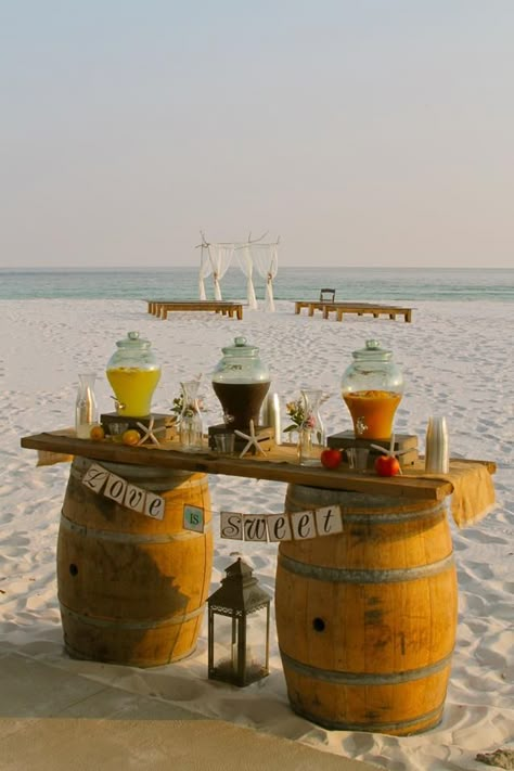 Rustic Beach Wedding Arbor and Farmhouse benches Beach Wedding Ceremony in the background with Barrel Bar Cooling Station set-up featuring Iced Tea, Lemonade, and Vigin Peach Bellini by White Sand Weddings www.mywhitesandwedding.com #FloridaBeachWeddings #EmeraldCoastBeachWeddings #BeachWeddingPackages Ceremony Benches, Beach Wedding Arbors, Rustic Beach Wedding, Wedding Arch Rustic, Beach Cocktails, Wedding Sand, Florida Beach Wedding, Wedding Arbour, Wine Barrels