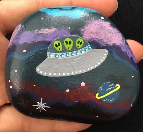 Space ship alien painted rock Space Rock Painting Ideas, Alien Rock Painting, Outer Space Painted Rocks, Alien Painted Rocks, Alien Spaceship Painting, Paw Crafts, Rich Garden, Trippy Alien Painting, Sidewalk Chalk Art