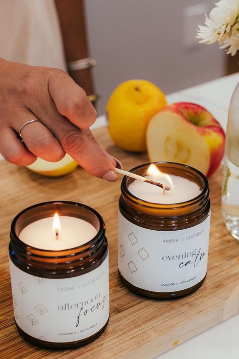 two amber glass jar candles lit on a cutting board